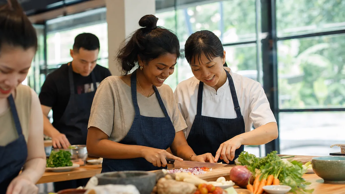A relaxed first-timer being guided through chopping at a bright Singapore cooking studio bench