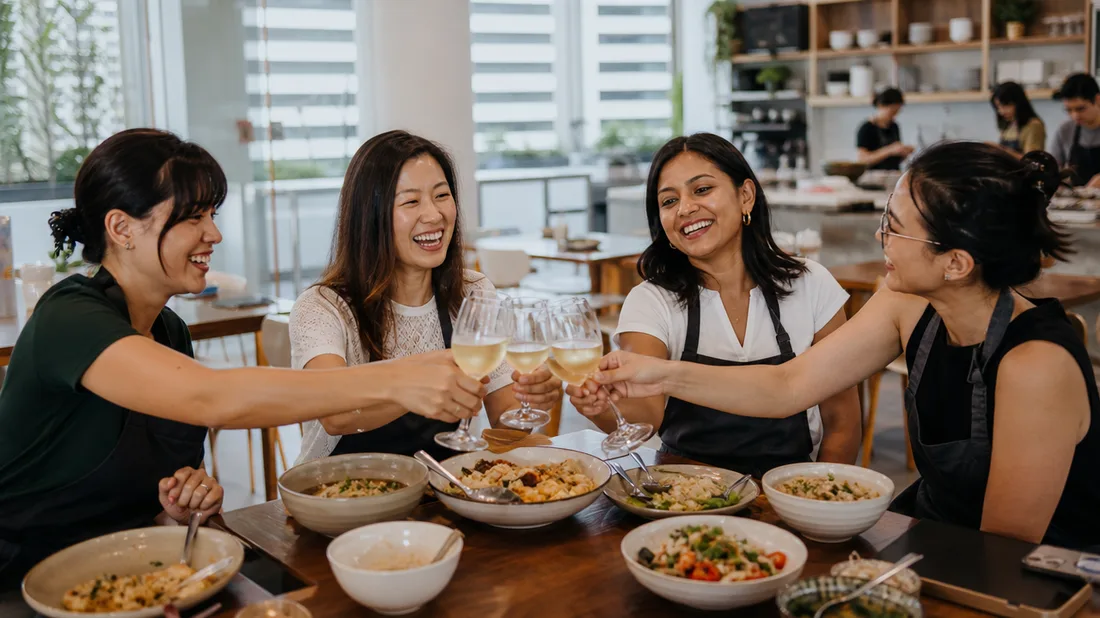 Friends raising a toast over the meal they cooked at a hen party cooking class in Singapore