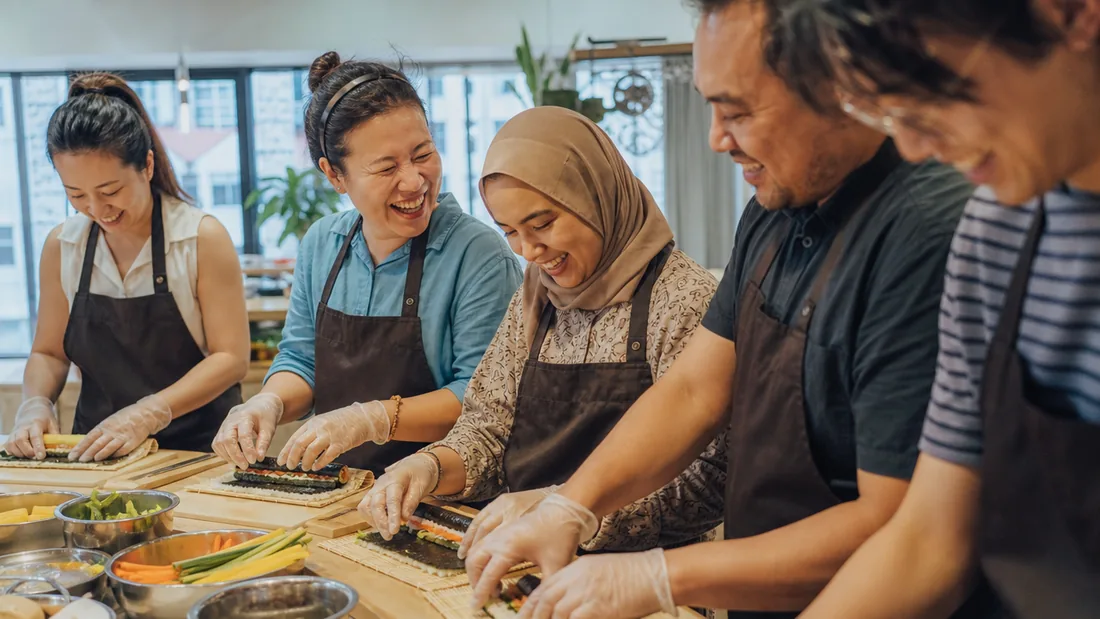 A team rolling kimbap and mixing bibimbap together at a bright Singapore cooking studio